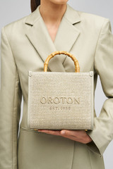 Profile view of model wearing the Oroton Lane Straw Tote in Laurel and Woven Straw With Leather Trim for Women . IP:3
