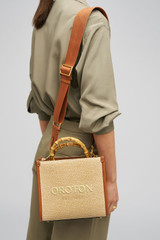 Profile view of model wearing the Oroton Lane Straw Tote in Amber and Woven Straw With Leather Trim for Women