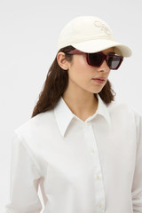 Profile view of model wearing the Oroton Oro Logo Cap in Antique White and High-quality 100% cotton material for Women . IP:2
