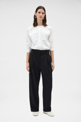 Profile view of model wearing the Oroton Tapered Pleat Pant in Black and 100% wool fabric for Women . IP:2