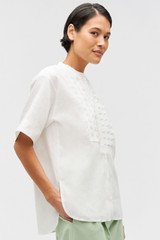 Profile view of model wearing the Oroton Lace Trim Smock Top in White and 100% linen for Women