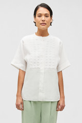 Profile view of model wearing the Oroton Lace Trim Smock Top in White and 100% linen for Women