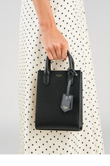 Profile view of model wearing the Accessories Ivy Mini Top Handle Tote in Black and Saffiano leather material for Women