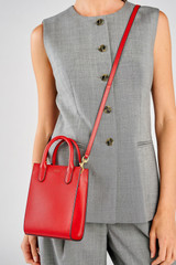 Profile view of model wearing the Oroton Ivy Mini Top Handle Tote in Dark Ruby and Saffiano leather material for Women