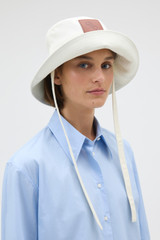 Profile view of model wearing the Oroton Nell Bucket Hat in Antique White and 100% cotton canvas fabric for Women . IP:3