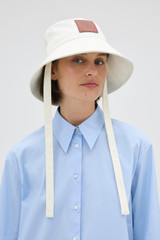Profile view of model wearing the Oroton Nell Bucket Hat in Antique White and 100% cotton canvas fabric for Women . IP:2