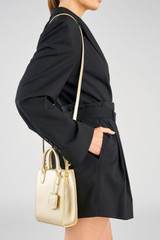 Profile view of model wearing the Accessories Ivy Mini Top Handle Tote in Gold and Saffiano leather material for Women