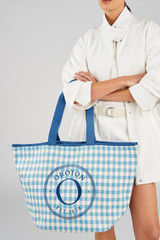 Profile view of model wearing the Oroton Kaia Shopper Tote in Cobalt Blue Check and Check straw material for Women