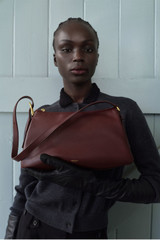 Profile view of model wearing the Oroton Cali Shoulder Bag in CURRANT and Premium smooth leather for Women .
