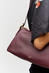 Profile view of model wearing the Oroton Cali Shoulder Bag in CURRANT and Premium smooth leather for Women .