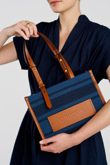 Profile view of model wearing the Oroton Sasha Small Tote in PRUSSIAN BLUE MIX and 100% polyester fabric for Women .