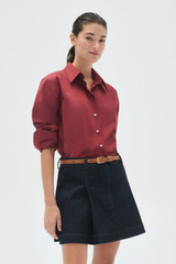 Profile view of model wearing the Oroton Wren Poplin Shirt in Rouge and Made from 100% poplin cotton  for Women