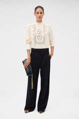 Profile view of model wearing the Oroton Fluid Cutwork Long Sleeve Top in Antique White and 75% acetate and 25% polyester blend fabric for Women . IP:2