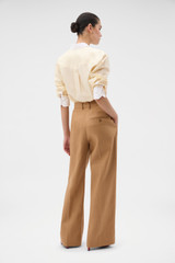 Profile view of model wearing the Oroton Pleat Pant in CAMEL and 100% heavyweight linen fabric for Women . IP:5