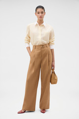 Profile view of model wearing the Oroton Pleat Pant in CAMEL and 100% heavyweight linen fabric for Women . IP:6