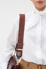 Profile view of model wearing the Oroton Logo Bag Strap in COPPER and Premium crackle leather and webbing material for Women . IP:2