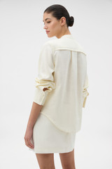 Profile view of model wearing the Oroton Long Sleeve Broderie Trim Shirt in SOFT CREAM and 100% heavyweight linen fabric for Women .
