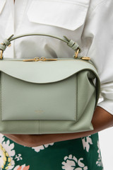 Profile view of model wearing the Oroton Mica Bowler in Gumleaf and Premium pebble grain leather for Women . IP:3