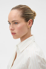 Profile view of model wearing the Oroton Daisy Pearl Studs in Worn Gold/Pearl and Premium brass material for Women . IP:2