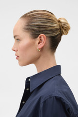 Profile view of model wearing the Oroton Rada Huggies in Gold and Premium brass material for Women . IP:2
