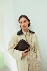 Profile view of model wearing the Oroton Essential Mac in Limestone and 77% cotton and 23% linen blend fabric body with a 100% leather collar for Women . IP:9
