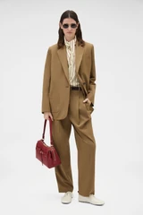 Profile view of model wearing the Oroton Tapered Pleat Pant in Dark Rye and 97% wool and 3% spandex blend fabric for Women . IP:6