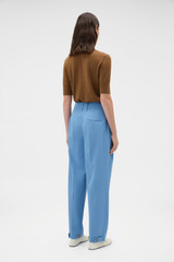 Profile view of model wearing the Oroton Tapered Pleat Pant in Porcelain Blue and 97% wool and 3% spandex blend fabric for Women . IP:4
