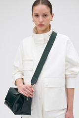 Profile view of model wearing the Oroton Logo Crackle Bag Strap in Shade Green and Jacquard webbing material for Women . IP:2