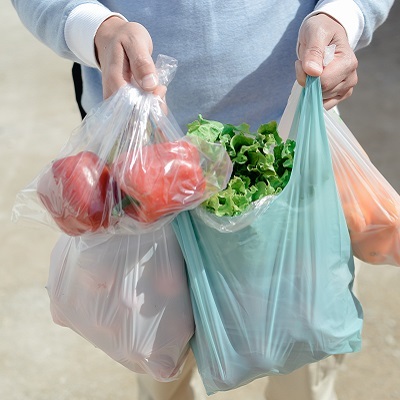 person holding plastic bags with produce