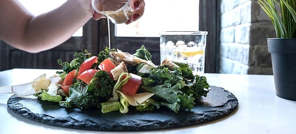woman pouring dressing over salad woman pouring dressing over salad