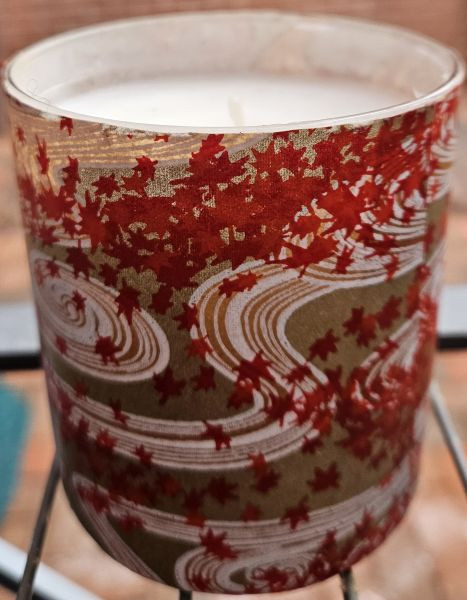 This candle has waves of tiny red leaves with white swirls on gold