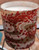 This candle has waves of tiny red leaves with white swirls on gold