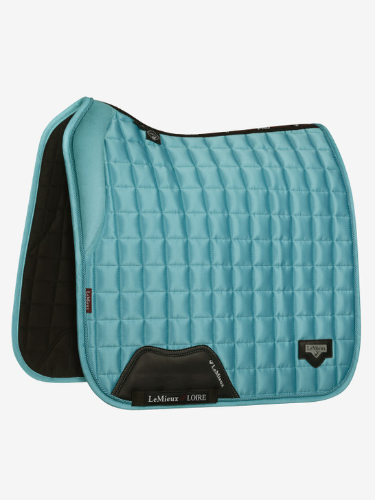 The Loire collection exudes sophistication and class - showing style without showing off! Woven Satin fabric gives a beautiful sheen to these pads whilst still benefitting from the wonderfully soft and breathable Bamboo lining. The 100% natural Bamboo material controls heat & sweat and wicks very efficiently. A soft memory foam collar supports the front panel of the saddle adding stability.

The whole pad benefits from a new extensively researched soft friction-free suede binding which is specially fabricated to smoothly contour the edges. This new technique helps retain the perfect saddle pad shape and binding profile.

The textured PU leather girth protection area is complimented by an embossed logo and carries the usual signature LeMieux lower girth strap with its inner locking loops. The piece de resistance of the Loire Dressage Square is its unique metal badge on a leather mount in the lower back corner.