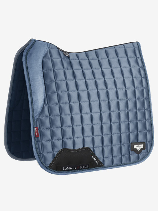 The Loire collection exudes sophistication and class - showing style without showing off! Woven Satin fabric gives a beautiful sheen to these pads whilst still benefitting from the wonderfully soft and breathable Bamboo lining. The 100% natural Bamboo material controls heat & sweat and wicks very efficiently. A soft memory foam collar supports the front panel of the saddle adding stability.

The whole pad benefits from a new extensively researched soft friction-free suede binding which is specially fabricated to smoothly contour the edges. This new technique helps retain the perfect saddle pad shape and binding profile.

The textured PU leather girth protection area is complimented by an embossed logo and carries the usual signature LeMieux lower girth strap with its inner locking loops. The piece de resistance of the Loire Dressage Square is its unique metal badge on a leather mount in the lower back corner.