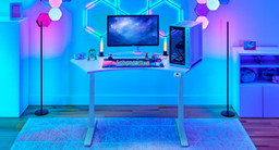 White 120-Degree UPLIFT Desk. Full gaming setup with a PC, monitor, desktop electronics, and colorful RGB accessories