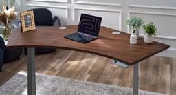 120-Degree desk features a walnut laminate top and a gray frame. Minimalist setup with a laptop and accessories