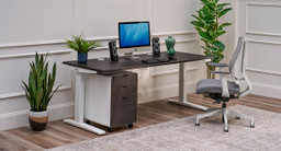 Modern home office showing a filing cabinet with gray drawer fronts positioned under an UPLIFT Standing desk