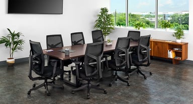 UPLIFT Desk Height Adjustable Conference Table shown in Figured Mahogany and black legs with the center leaf installed, and Facet Ergonomic Chairs in black