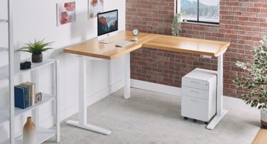 A White Oak L-Shaped desktop and white frame coordinate with UPLIFT Desk accessories