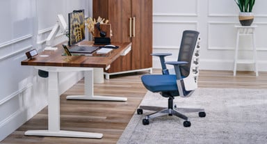 UPLIFT V3 Standing Desk with a Walnut Butcher Block desktop, a Vert Ergonomic Chair, and a MoPac Wardrobe in Walnut Laminate
