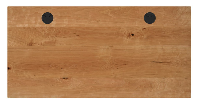 A wooden desk top with two black circular ports near the top edge.