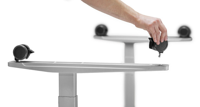 Two desks with wheels and a hand adjusting a caster