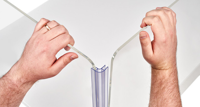 Pair of hands pulling apart a clear acrylic desk divider channel with joints