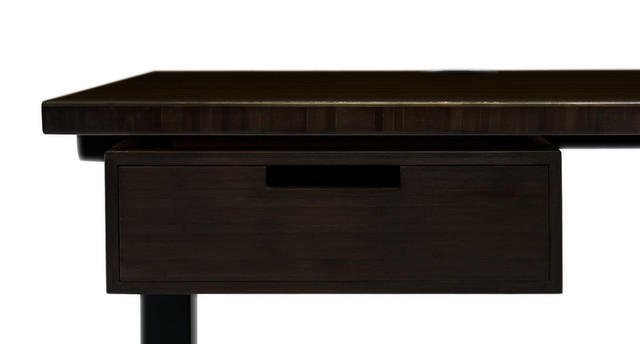A dark wood desk with a sliding drawer front and a black leg visible; the top surface extends beyond the drawer