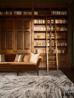 David Rockwell Falls Graphite rug, swirling charcoal and ivory pattern in an oak-panelled library with a velvet sofa