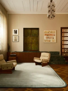 The Rug Company Arc rug, Spruce colourway, styled in a living room with a dark wood console and marble accent wall