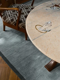 Margo rug in Lake, styled vignette with a patterned armchair and round stone table