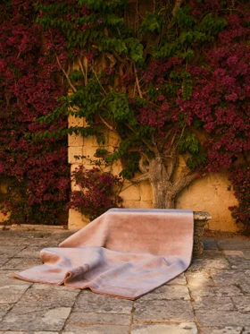 Mohair Sheared rug in Orchid, rolled and shown against garden greenery