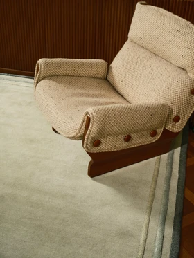 Arc rug in Spruce, close-up styled vignette with an upholstered armchair