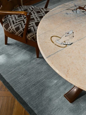 Margo rug in Lake, styled vignette with a patterned armchair and round stone table
